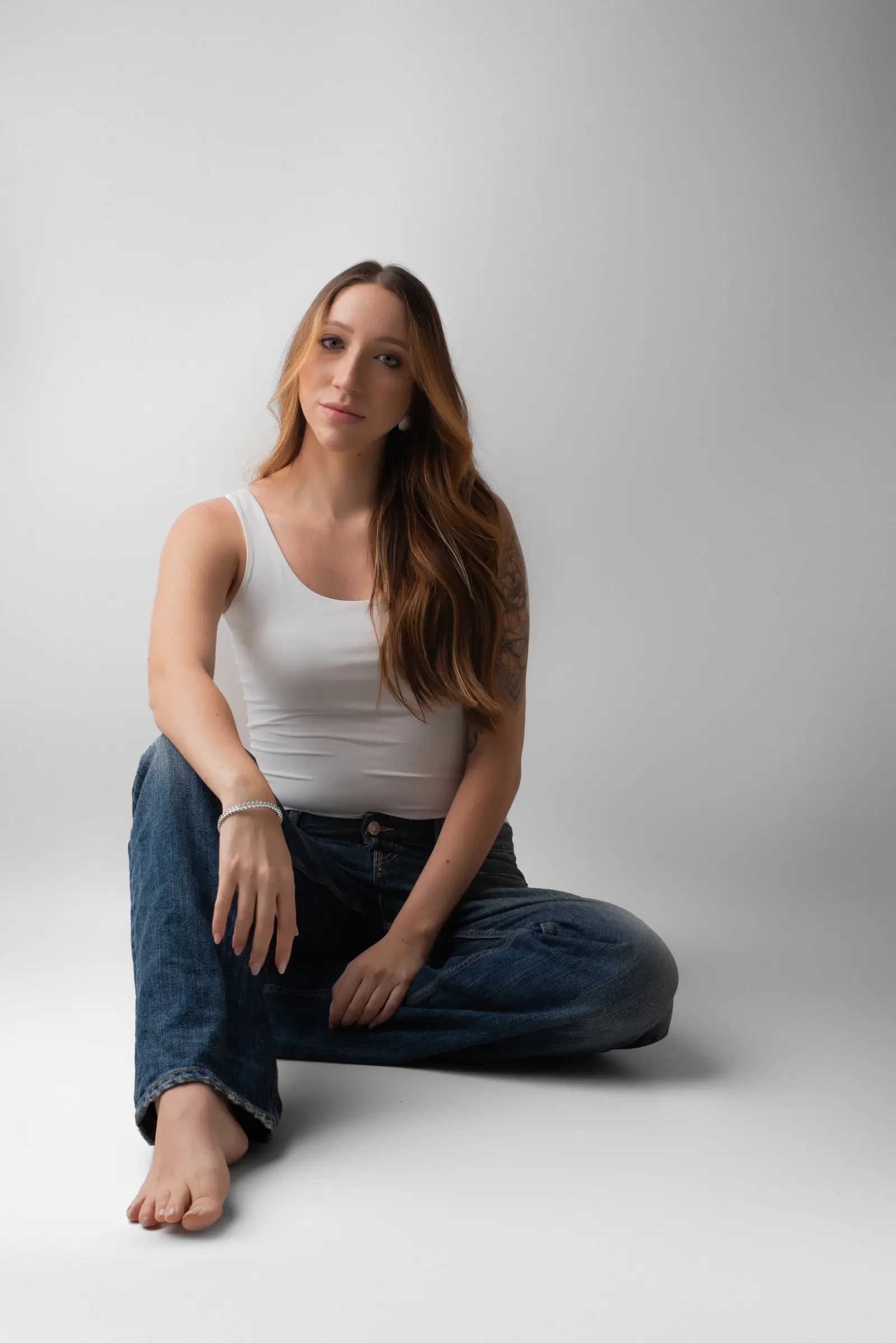 Giulia Toledo sentada no chão do estúdio, olhando para a câmera