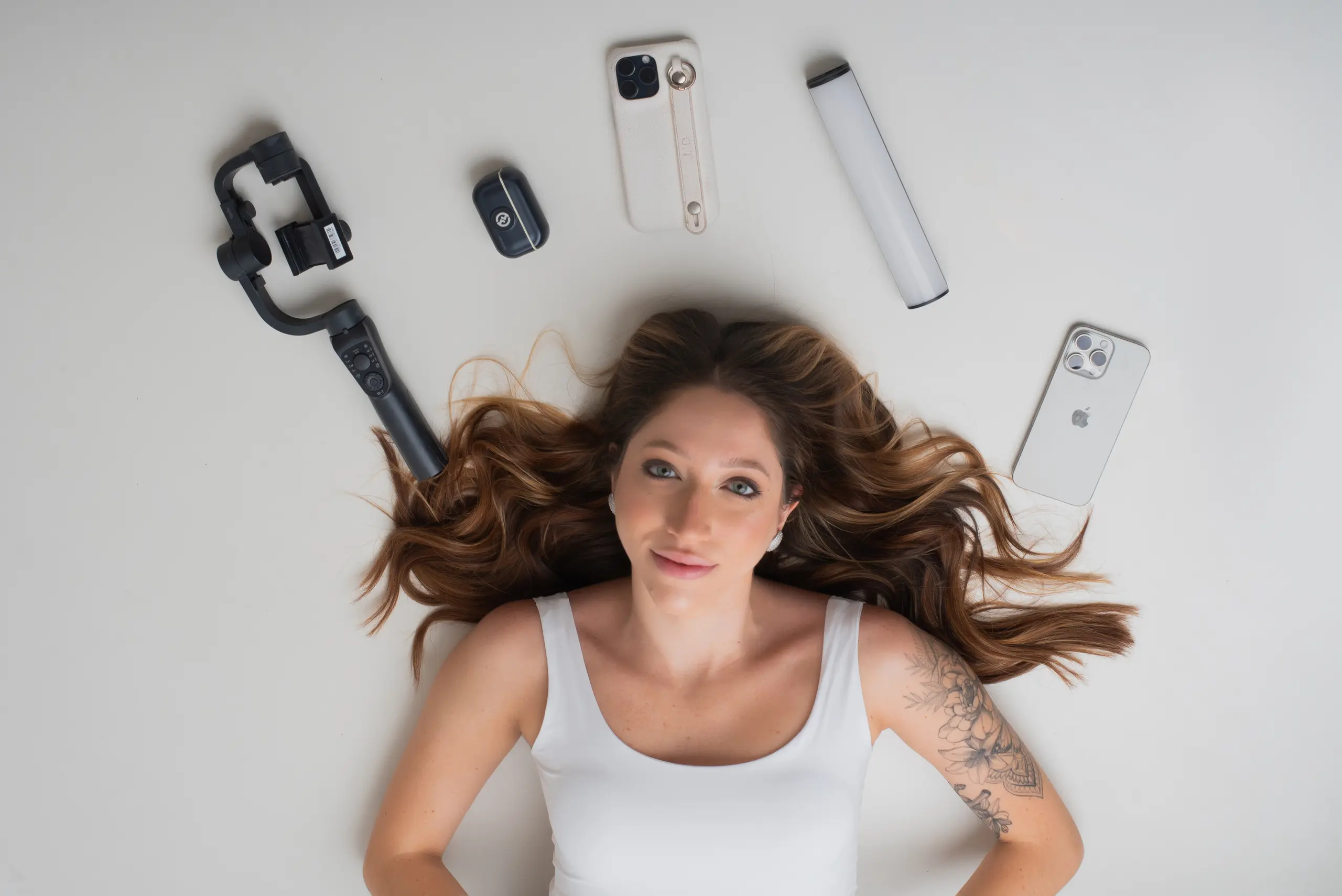 Giulia Toledo deitada cercada pelos equipamentos de um kit de criação de conteúdo